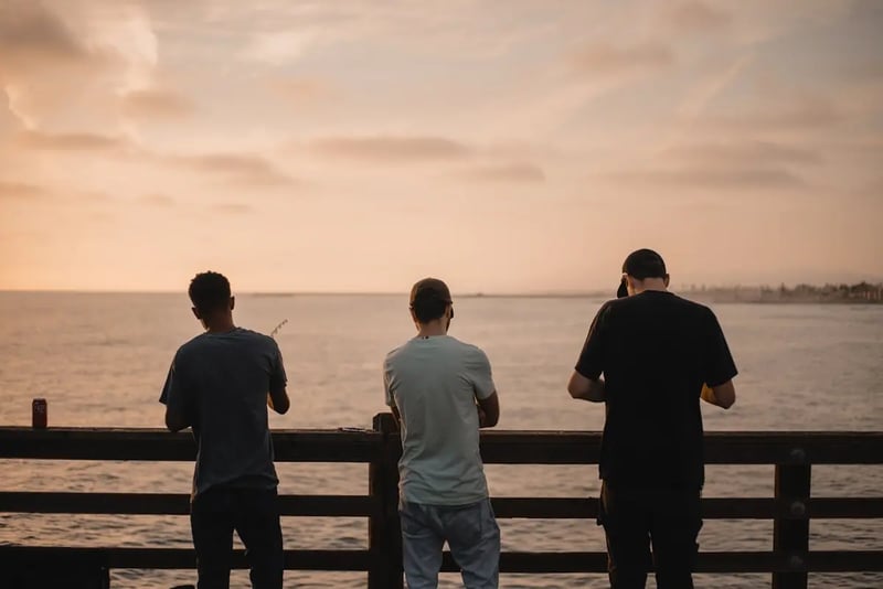 Three people standing side by side overlooking water and supporting each other