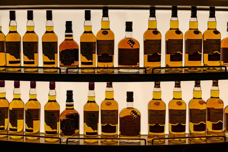 A variety of alcoholic drinks on a bar shelf