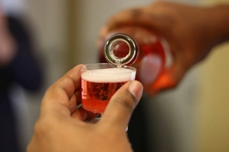 A person pouring wine into a clear glass while measuring the volume
